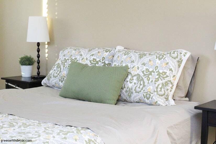 Green, blue and white bedspread with green throw pillow and khaki sheets