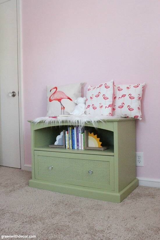 A green TV stand turned book storage in a girl's pink nursery