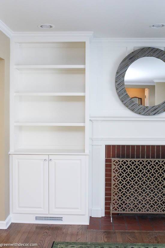 White built-in bookshelves around a brick fireplace