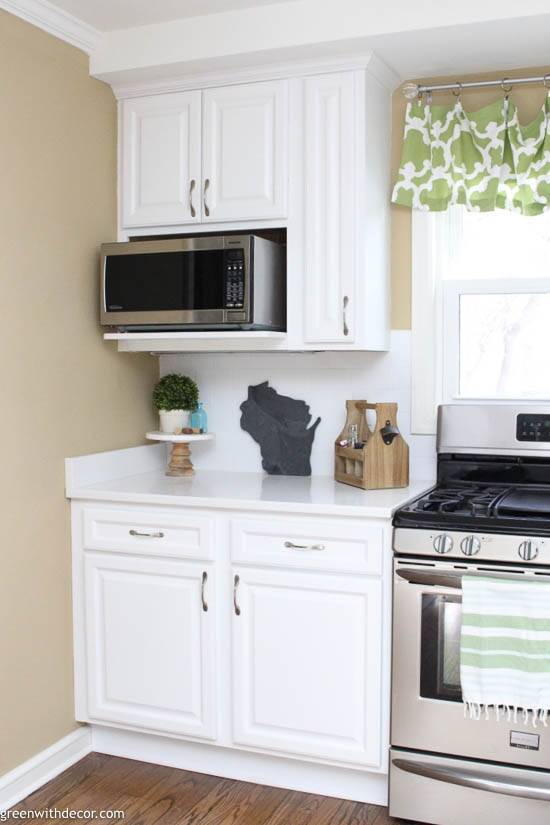 A microwave sits in a built-in microwave cabinet in a bright white farmhouse style kitchen.