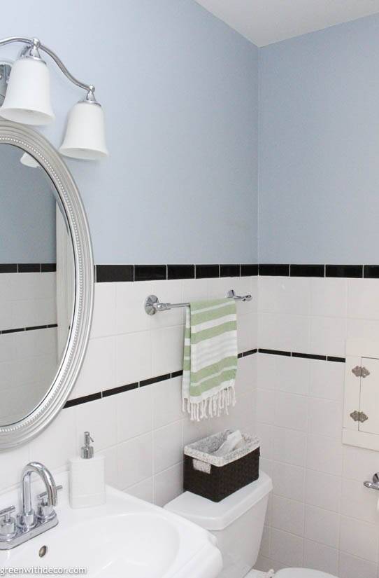 A blue bathroom with black and white tile and silver hardware