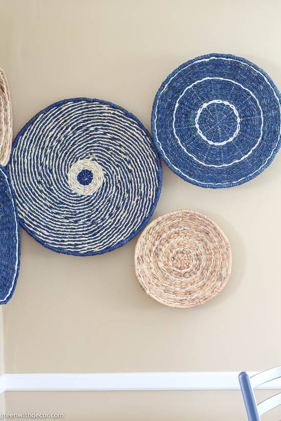 Blue, tan and white seagrass baskets hung on a tan wall