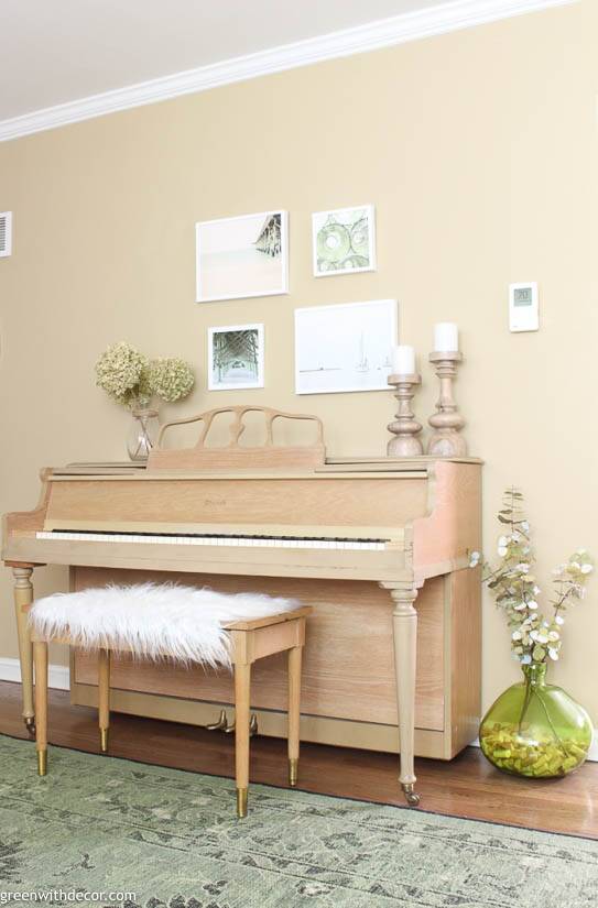 A coastal gallery wall above a piano in a tan room