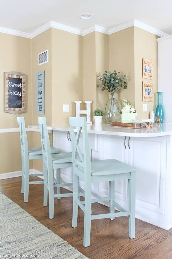 A white and tan coastal kitchen with painted barstools