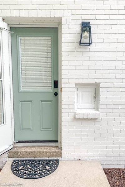 White brick house with blue door and black light fixture