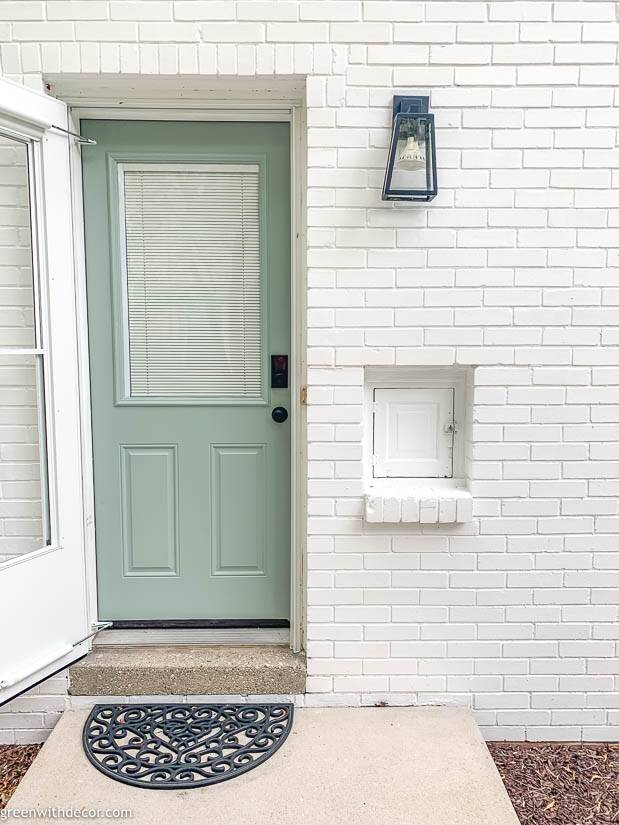 White brick house with blue door and black light fixture