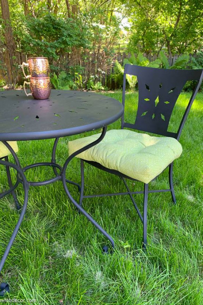Painted bistro set with green cushions and copper mugs