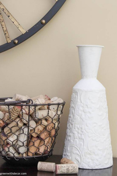 A painted vase next to a basket of wine corks