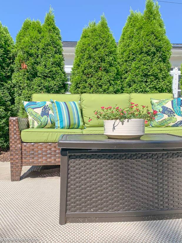 Summer patio with a green couch, white planter and blue and green pillows