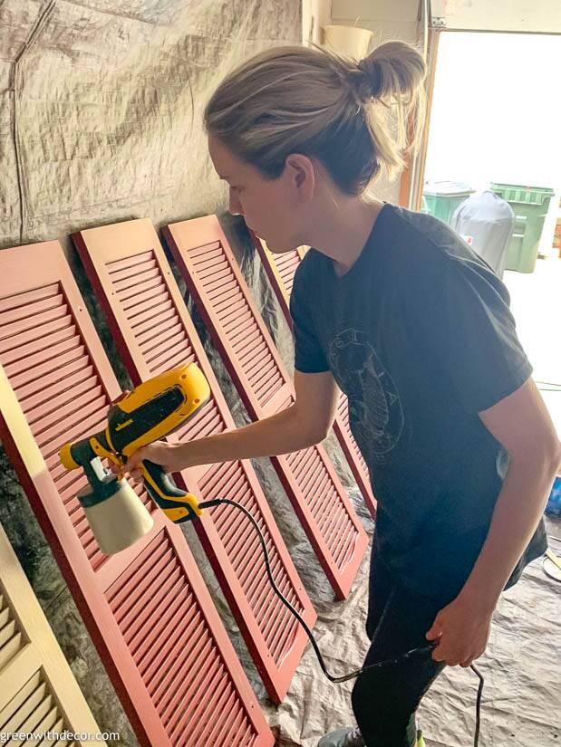 Girl painting shutters with a Wagner paint sprayer