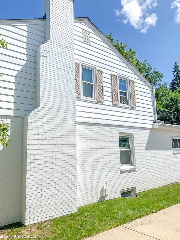 A white brick house with tan painted shutters