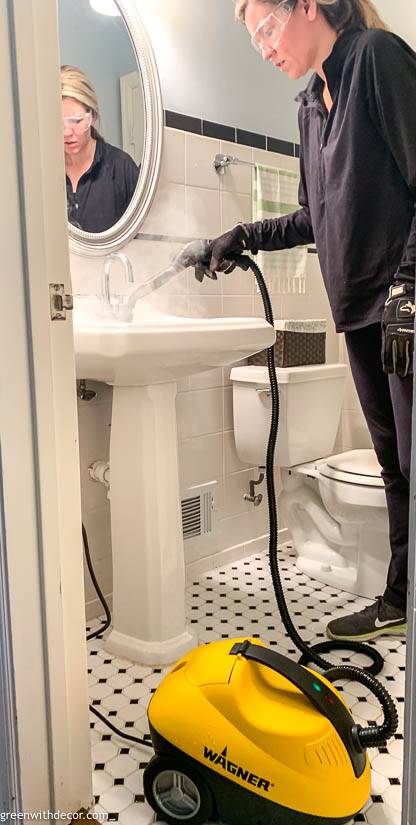 Girl cleaning a white and black bathroom with a steam cleaner