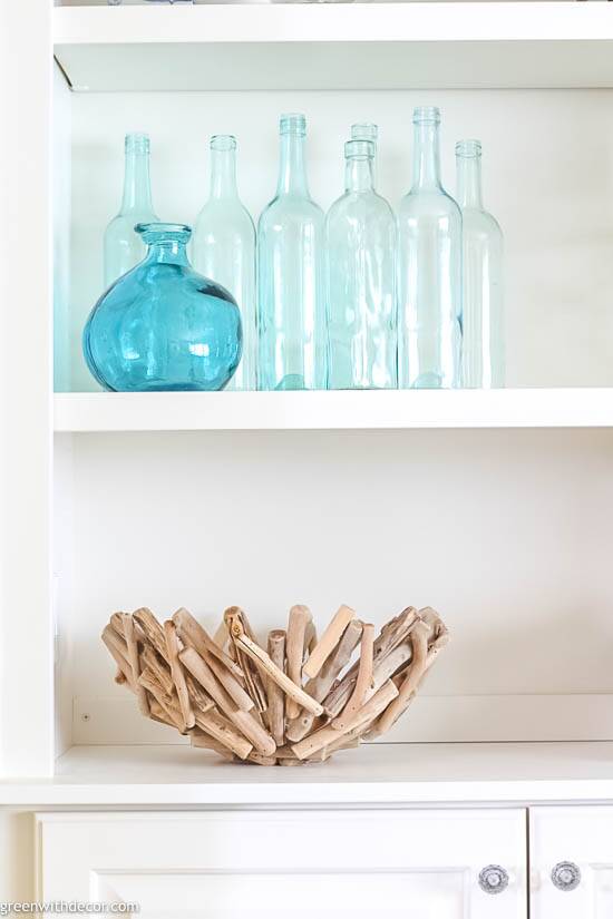 Coastal bookshelf decorating ideas: a driftwood bowl and aqua glass vases