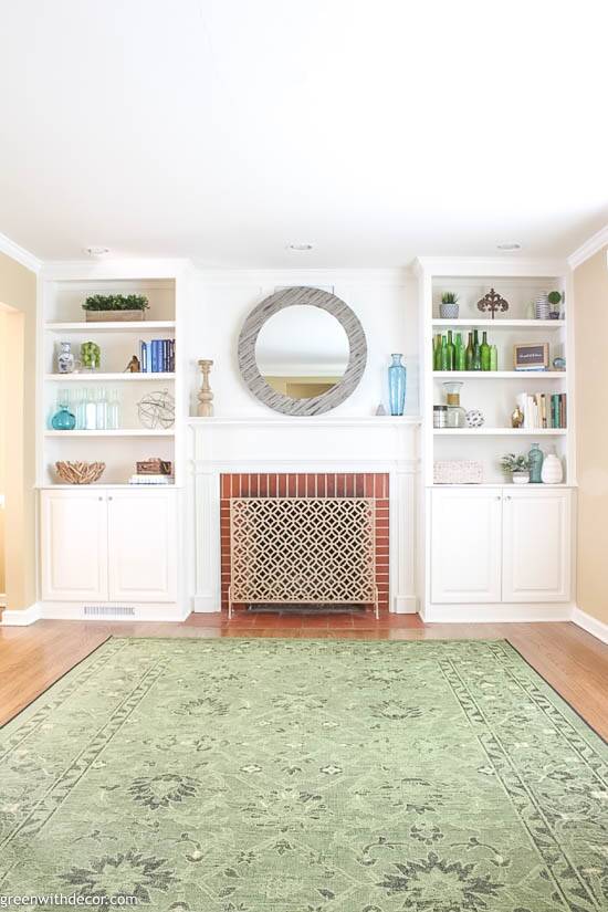 White bookshelves decorated with costal pieces around a red brick fireplace