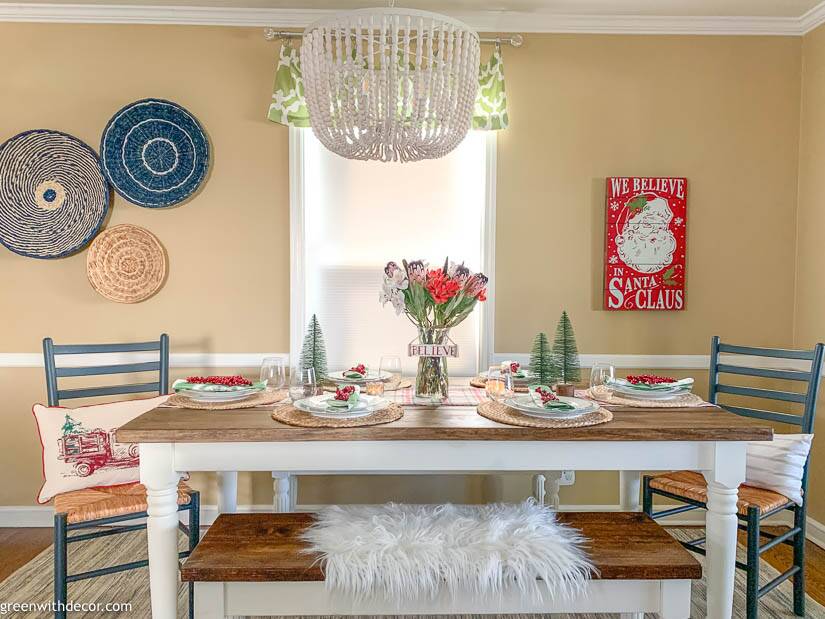 A coastal dining room with a Christmas centerpiece and white wood chandelier