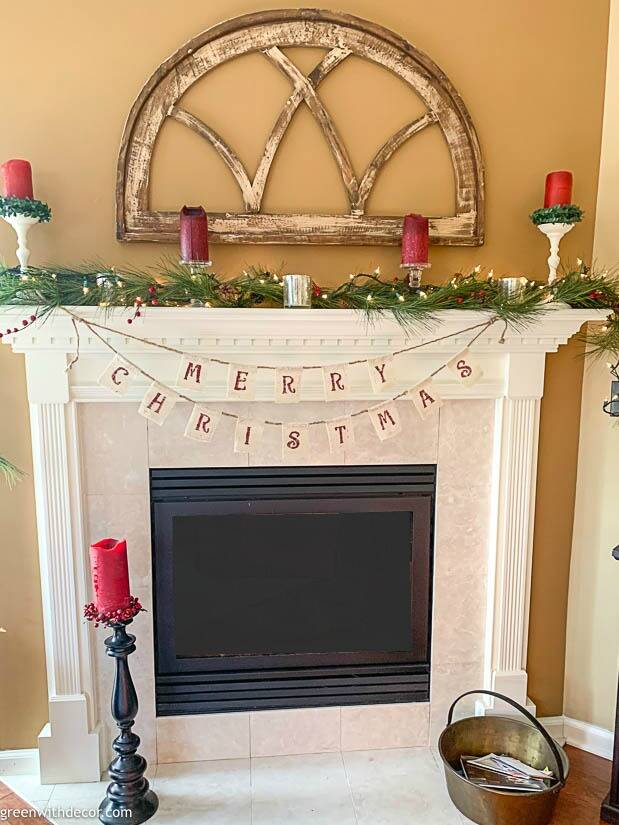 A DIY Christmas mantel on a white mantel with garland and red candles