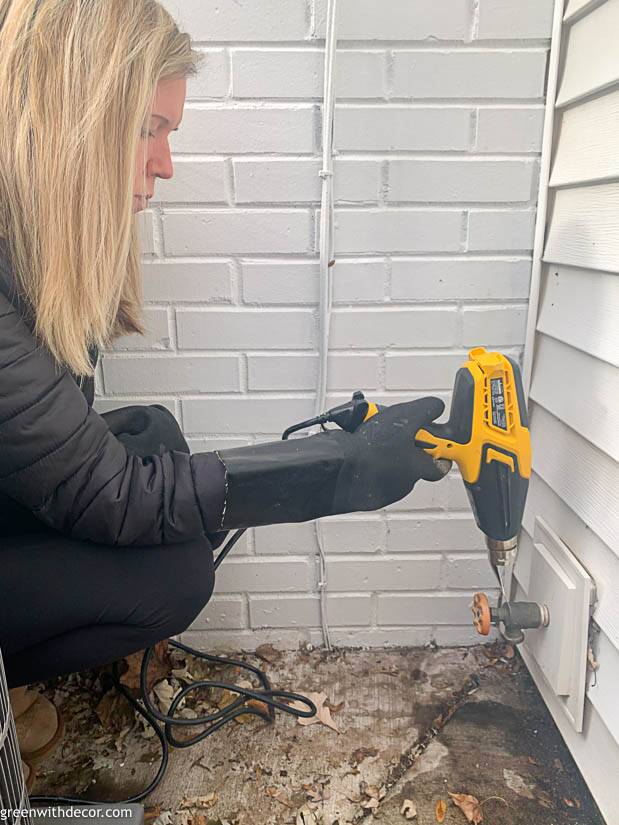 Girl using a heat gun to thaw an outdoor spigot