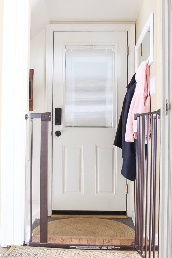 A small entryway with a white door and coats hung on the wall.