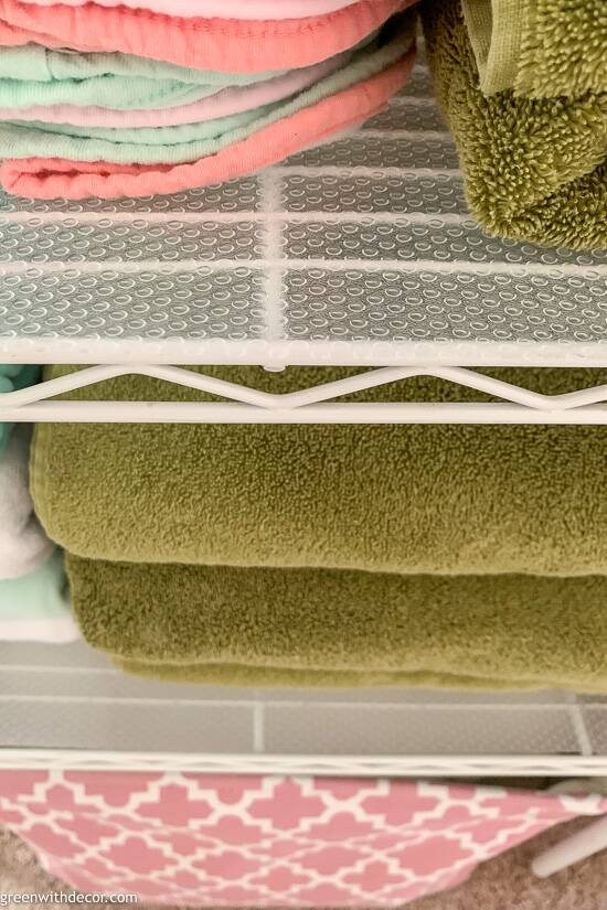 Towels on a drawer liner on a metal shelf