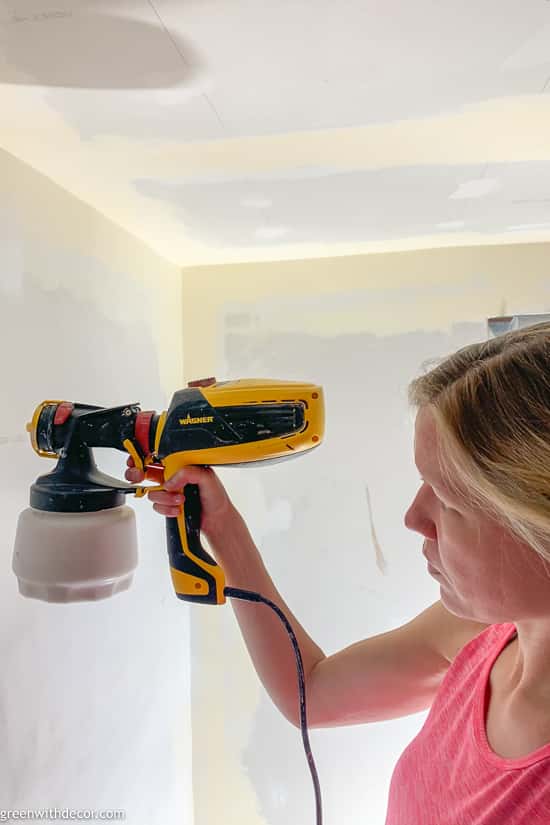 Girl painting a room with a paint sprayer