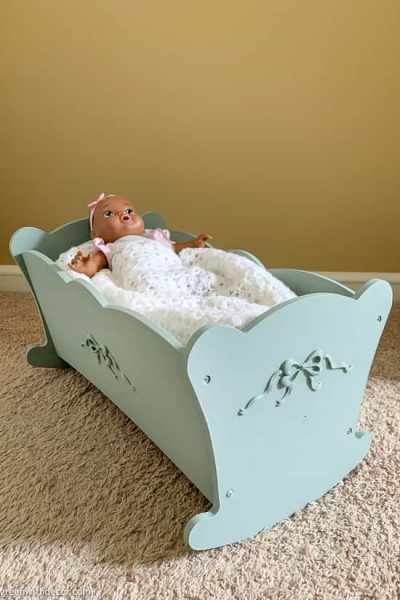 Blue painted doll cradle with doll