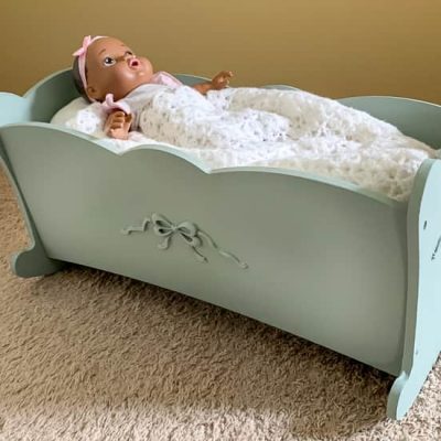 Painted blue doll cradle near tan wall