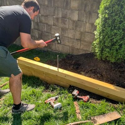 Guy pounding rebar into DIY planter box