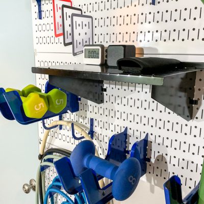 Storing gym equipment on white pegboards